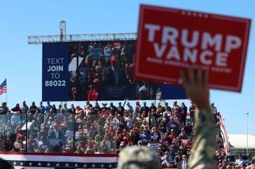 A man holds up a Trump-Vance sign at a rally by former president Donald Trump in Mosinee, Wisconsin